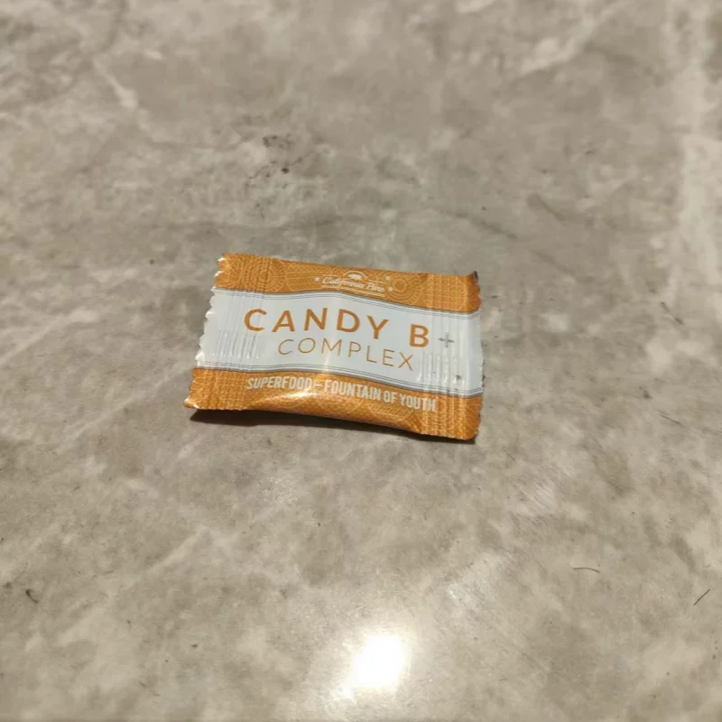Candy B Complex bar in an orange and white wrapper on a grey surface