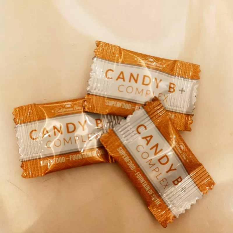 Three individually wrapped Candy B Complex bars on a cream surface