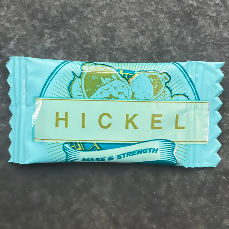 HICKEL Mass and Strength bar in a turquoise wrapper on a dark surface