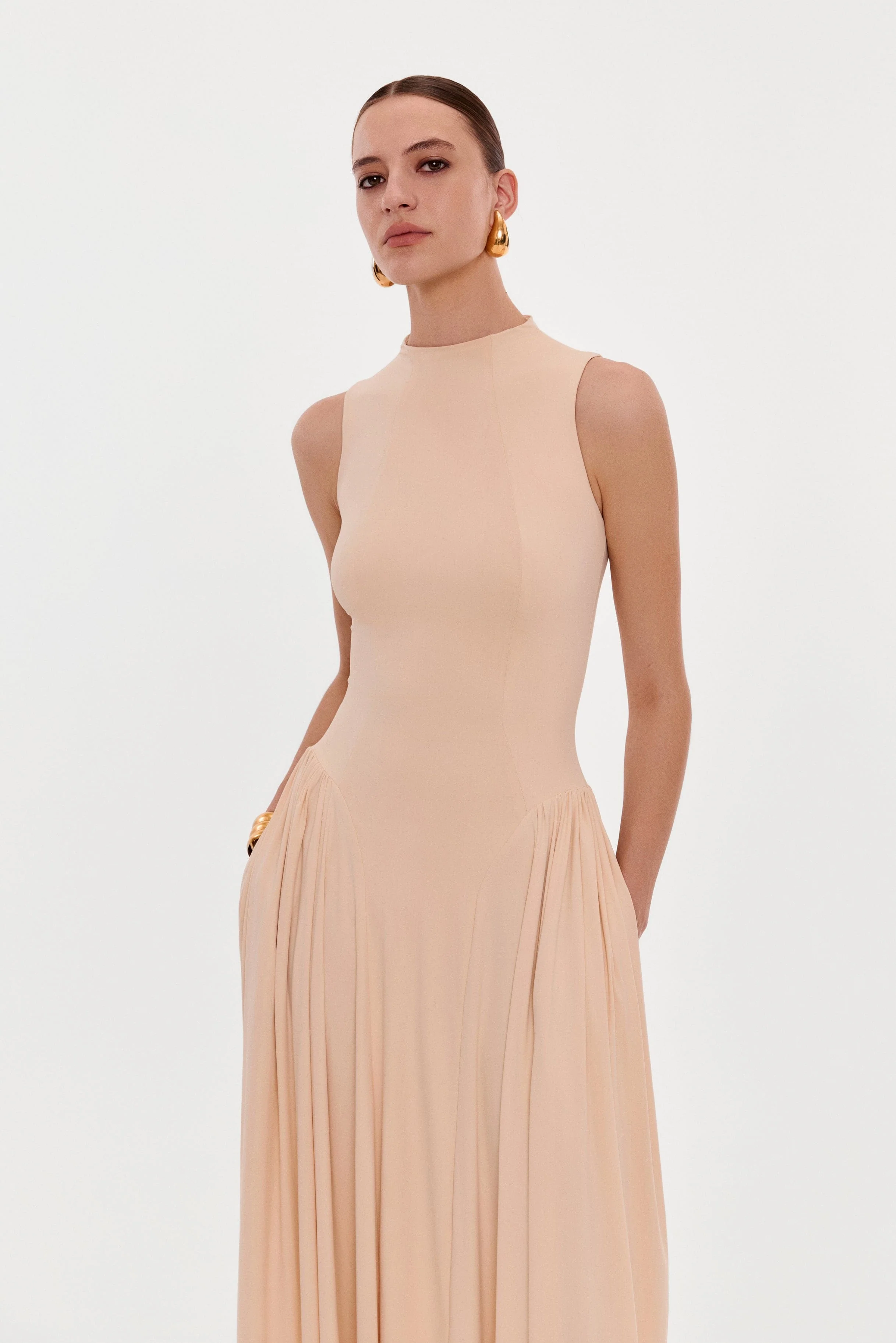 Nude sleeveless mock neck dress with a pleated maxi skirt