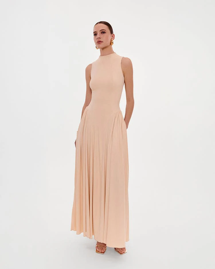 Nude sleeveless mock neck dress with a pleated maxi skirt