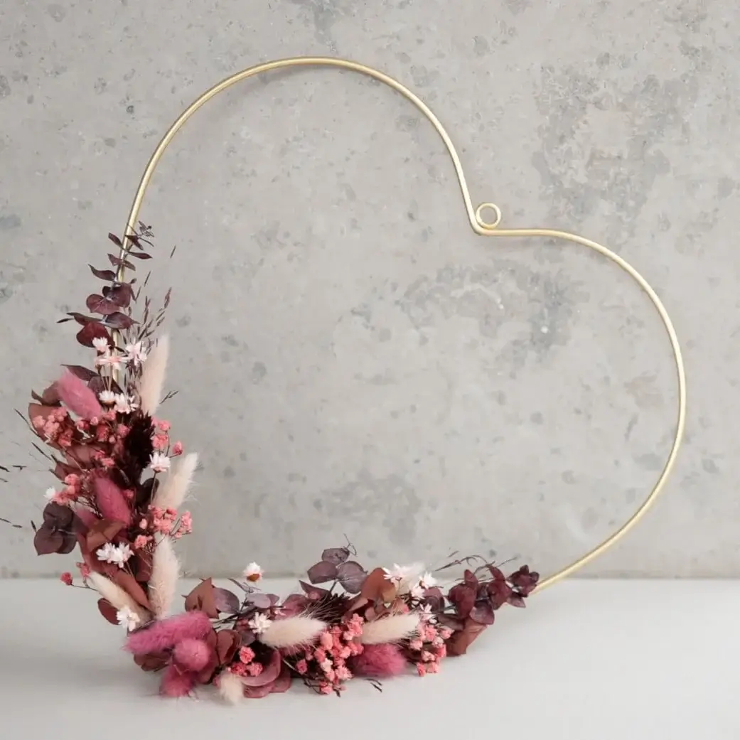 Liebeserklärung in Blüten: Goldenes Herz mit Trockenblumen in Rosa und Rot